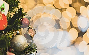 Close up shot of red glossy Christmas eve decor items hanging decorating on green Xmas pine tree branch with sphere balls and