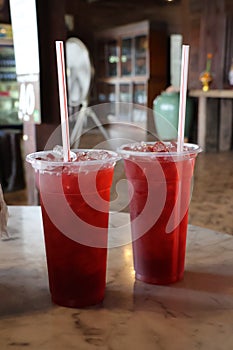 Close-up shot of red juice in a plastic glass with a straw, a refreshing drink concept in a throwable glass.