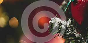 Close up shot of red present stocking gift bag hanging decorating with fake snow on green Christmas pine tree branch and leaves in