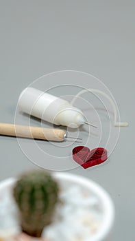 A close-up shot of a red quilled paper heart on a gray surface