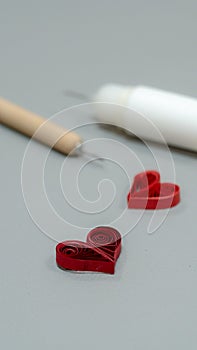 A close-up shot of a red quilled paper heart on a gray surface