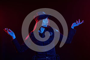 Close-up shot of a redheaded female police officer is posing for the camera against a black background with red and blue