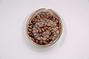 Close up shot of roasted coffee beans in a shell bowl isolated on white background with copy space