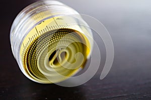 Close up shot of a rolled yellow measuring tape in centimeters on a wooden surface