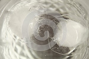 Close up shot of round-shaped ice cubes floating and melting in a transparent glass of water