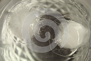 Close up shot of round-shaped ice cubes melting in a transparent glass of water