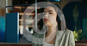 Close up shot selective focus on young buisness lady woman sitting at table wearing wireless headphones listens to music
