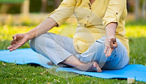 Close up shot of senior woman doing yoga or meditation during morning at park - concept of mindfulness, self care and