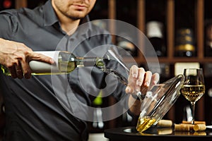 Close up shot of serious sommelier pouring white wine in decanter