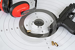 Close up shot of a shooting target and bullseye with bullet holes with automatic pistol gun and cartridge bullet.