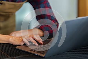 Close-up shot of shop owner's hands typing on laptop computer. Because always responding to customer chats that come