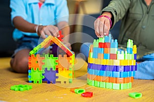 Close up shot of siblings kids playing with toys building blocks while sitting at home - concept of entertainment