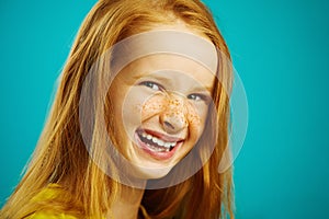 Close-up shot, sincere laughter of cute baby girl with red hair and freckles on blue isolated. Concept of happiness