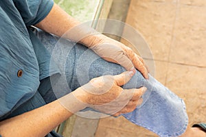 Close up shot of sitting seniors knees with hands touching or grabbing due to feeling pain and hurt shows elderly disease due to