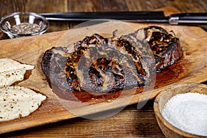Close up shot of sliced roasted liver on wooden platter, next to garlic sauce