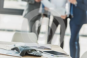 close-up shot of speakerphone with blurred business people on background