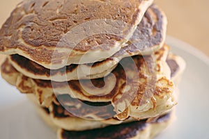 Close-up shot of stack of homemade pancakes, fresh and hot prepare before pouring syrup in white dish on wooden table, selective