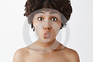 Close-up shot of tender and gentle silly naked woman with afro hairstyle folding lips and awaiting for passionate kiss