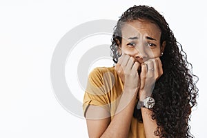 Close-up shot of terrified scared timid african american woman frowning trembing from fear as seeing spooky movie scene