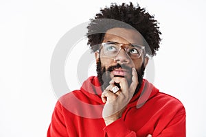 Close-up shot of thoughtful african american man rubbing beard and looking at upper left corner focused, thinking