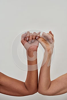 Close up shot of two female hands making pinky swear. Promise hand gesture isolated over light background