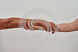 Close up shot of two female hands rescuing or holding each other strongly isolated over light background