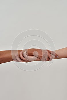 Close up shot of two female hands rescuing or holding each other strongly isolated over light background