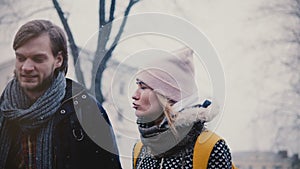 Close-up shot of two happy relaxed Caucasian friends walking, talking and smiling in the street on cold snowy winter day