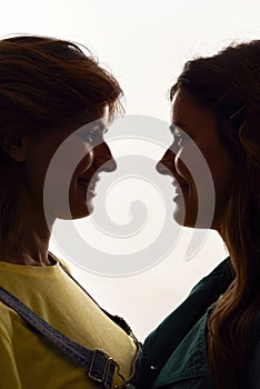 Close up shot of two young girls, twin sisters smiling at each other, posing together, standing face to face isolated