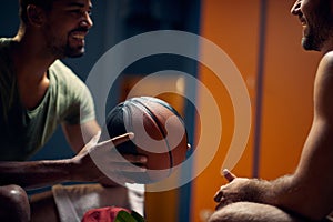 Close up shot of two young sporty men talking in gym dressing room, sitting face to face