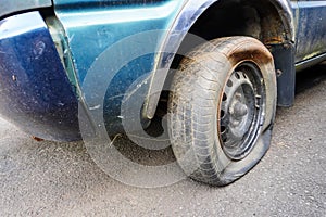 Close up shot of unbranded flat tire on old and rusty car