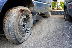 Close up shot of unbranded flat tire on old and rusty car