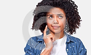 Close up shot of uncertain African American woman has puzzled expression, frowns her face and looking up.