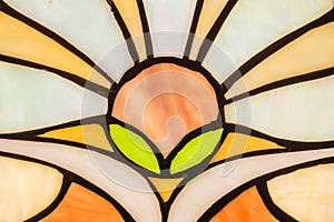Close-up shot of varicoloured stained glass window backlit by the sun. Part of a stained from glass orange, white and green glass