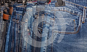 Close up shot of various blue Jeans on a hanging rack in the clothes store. Shopping and clothing store concepts