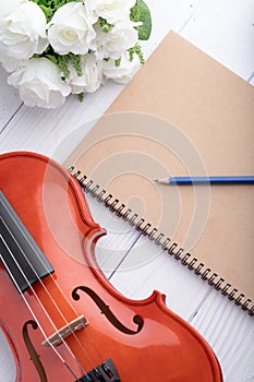 Close-up shot violin orchestra instrumental and notebook over white wooden background select focus shallow depth of field