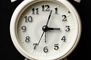 Close-up shot of white alarm clock over dark background