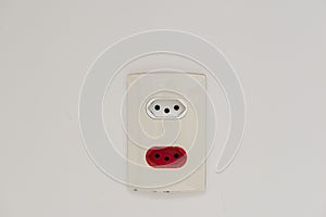 Close Up shot of a white wall plug with a Swiss and Brazilian standard socket