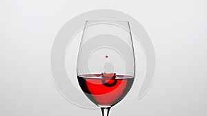 Close up shot of wine glass isolated on white background in studio. Goblet filled with red wine, droplets of wine