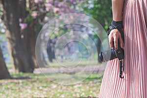 Close-up shot of woman hand holding  camera. Young hipster photographer preparing shooting camera in outdoor nature landscape