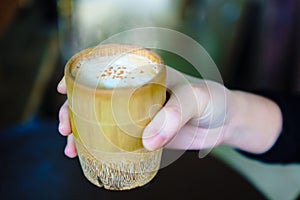 close-up shot of a woman hand holding a coffee cup made of a bamboo.