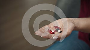 Close up shot of a woman holding many pills in her open hand, showing it to the camera