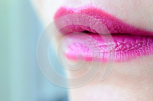 Close up shot of woman lips with glossy fuchsia lipstick