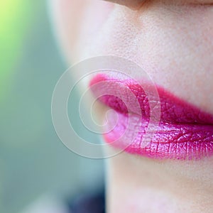 Close up shot of woman lips with glossy fuchsia lipstick