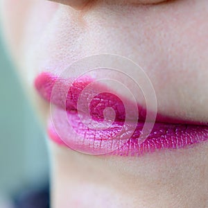 Close up shot of woman lips with glossy fuchsia lipstick