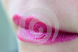 Close up shot of woman lips with glossy fuchsia lipstick