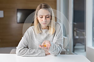 Close-up shot of a woman`s hand holding a few yellow pills