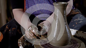 Close up shot of the woman`s hands, the mater forms the shape of a clay pot with tools, the product stands on a potter`s