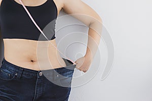 Close up shot of woman with slim body measuring her waistline and torso. Healthy nutrition, diet and weight losing concept
