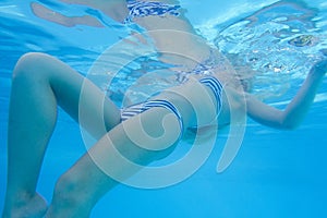 Close-up shot of a woman swimming underwater in the pool.